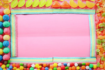 Wall Mural - Frame of colorful candies on wooden background