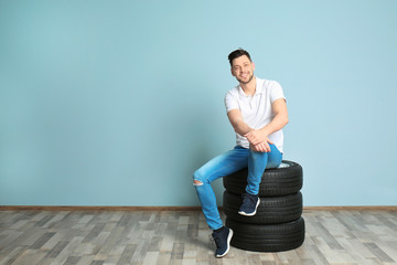 Wall Mural - Young man with car tires on color wall background