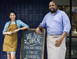 © Rawpixel.com - Cheerful business owners standing with open blackboard