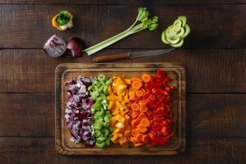 Poster - Chopped vegetables arranged on cutting board on wooden table, top view