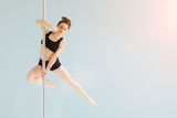 Beautiful pole dancer performing in the studio. Seria photo of middle aged red hair woman in black bra and shorts workout pole dance on air with different poses. Gray background.