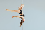 Beautiful pole dancer performing in the studio. Seria photo of middle aged red hair woman in black bra and shorts workout pole dance on air with different poses. Gray background.