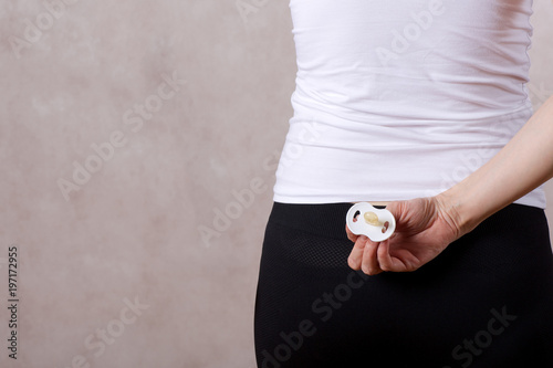 Fotografia, Obraz Young woman between 30 and 40 years old is hiding a soother behind her back