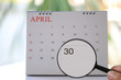 © meepoohyaphoto - Magnifying glass in hand on calendar you can look Thirty day of month,Focus number thirty in April.