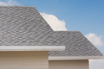 Sticker - Roof shingles on top of the house against blue sky with cloud, dark asphalt tiles on the roof background.