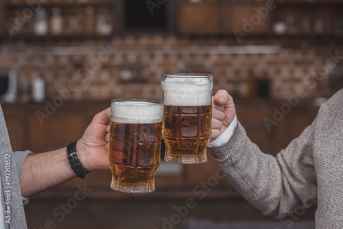 Plakat przycięte zdjęcie dorosłego syna i starszy ojciec clinking z szklanki piwa w domu
