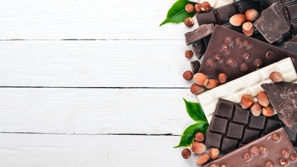 A set of milk chocolate and black chocolate hazelnuts. On a white wooden background. Copy space for text.