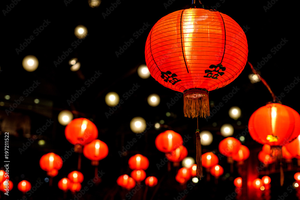 a spattering of red Chinese paper lanterns all lit up for Chinese New Year - obrazy, fototapety, plakaty 