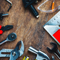 Set of construction tools on wooden board as wrench, hammer, pliers, socket wrench, spanner, tape measure, electric drill,safety glasses, screwdriver