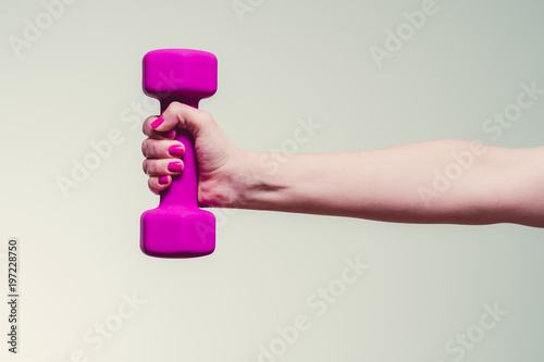 Photographie female lifting magenta colored dumbbell against teal background