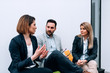 © bnenin - Three collegues talking while sitting in front of white background.