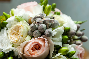 Wedding rings and wedding boquet in background