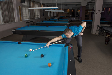 Wall Mural - Top view of a pool player performing a shot on a ball with chalk on the side of the table.