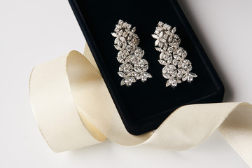 Wall Mural - Pair of platinum earrings with diamond earrings, close-up. Luxury female gold jewelry