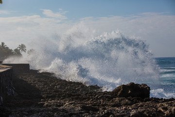 Wall Mural - tropical beach break, ocean wave crushing stone coastline, water splashes