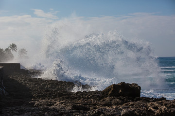 Wall Mural - Tropical beach break, ocean wave crushing stone coastline, water splashes