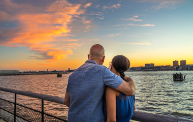 Couple watching beautiful sunset at riverside park, Manhattan NY