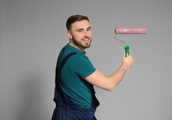 Sticker - Young male decorator with paint roller on color background