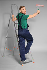 Wall Mural - Young male decorator with paint roller on color background