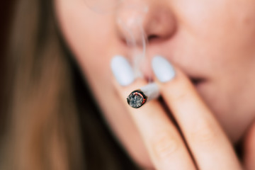 smokes weed cannabis, A woman joint in his hands. Smoke on a black background. Concepts of medical marijuana use and legalization of the cannabis.