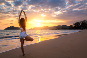 Wall Mural - Travel woman yoga on beach in sunset