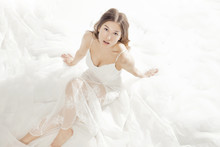 Charming Girl Dressed In A White Dress Lean Against White Fabric