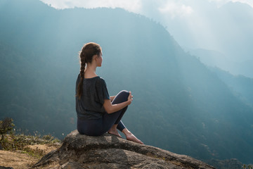 Woman sits on mountain cliff