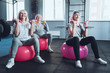 © Viacheslav Yakobchuk - Full of energy and joy. Focused senior female friends smiling while taking an exercise class and training with dumbbells while sitting on fitness ball in a gym.