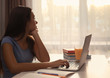 © Africa Studio - Cute teenager girl looking out the window while doing homework indoors