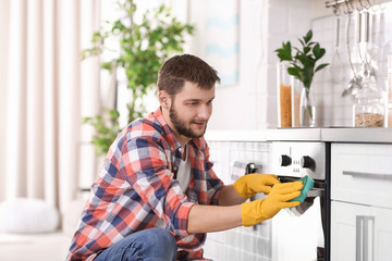 Poster - Young man cleaning oven in kitchen