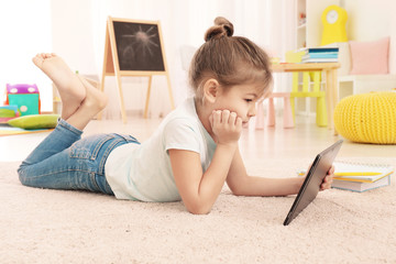 Canvas Print - Cute little girl using tablet PC while doing homework indoors