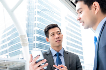 Wall Mural - Businessmen discussing information on smartphone outdoors