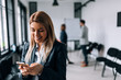© bnenin - Smiling business woman using phone during a break. Collegues standing in the background