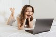 © Drobot Dean - Portrait of an excited young woman lying in bed at home