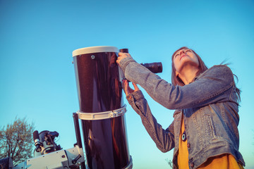Wall Mural - cute young woman holding astronomical telescope and looking at the sky.