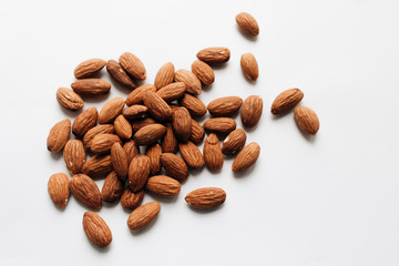 Pile of almonds on white background with copy space, healthy eating concept