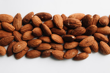 Pile of almonds on white background with copy space, healthy eating concept