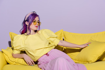 Wall Mural - beautiful young woman in yellow eyeglasses sitting on yellow couch