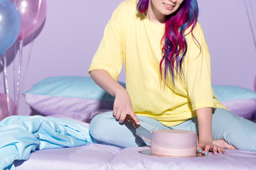 Wall Mural - cropped shot of smiling young woman cutting birthday cake in bed