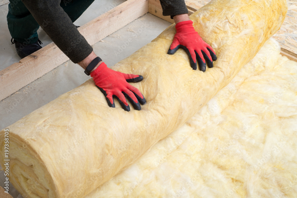 Work composed of mineral wool insulation in the floor, floor heating insulation , warm house, eco-friendly insulation, a builder at work - obrazy, fototapety, plakaty 