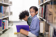 © Nattanon - Little Asian spectacles Boy and his happy African boy. Happy Children Learning Class in Library. Development of Human Resources in Education Concept. Setup studio shooting.