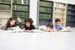 © Nattanon - Happy kids and bored kids reading on the floor, Education lifestlye in the Library. Young people explore lifestlye in the Library. Setup studio shooting.