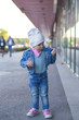© ondrooo - A little girl in jeans wear shows on the street