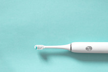 White Electric Toothbrush On Blue Background With Copy Space. The Concept Of Good Mouth Hygiene.