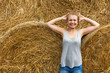 © AnastazjaSoroka - A smiling young woman with blond hair stands on the background of haymaking.