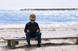 boy playing in the tablet on the seashore in the spring