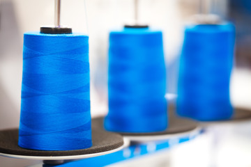 Fototapete - Close-up bobbins with blue colored thread for industrial textile machines