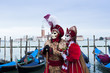 Couple of carnival masks in St. Mark's Square in Venice. In the background the church of San Giorgio. Italy