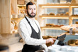 © rh2010 - Portrait of a handsome seller in uniform standing in the small and beautiful store with bakery products