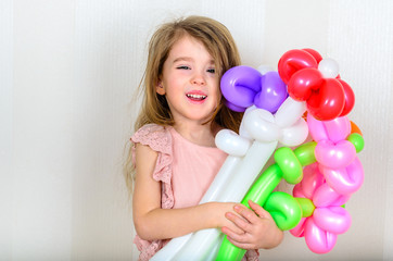 a charming girl with dark eyes, dressed in a gently dress and holding a large bouquet of flowers from inflatable balls of pink, orange, red and lilac